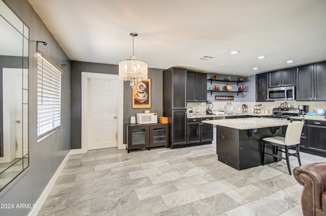 kitchen featuring appliances with stainless steel finishes, a kitchen bar, backsplash, hanging light fixtures, and a kitchen island