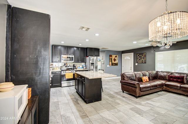 kitchen with light stone counters, appliances with stainless steel finishes, a kitchen breakfast bar, decorative light fixtures, and a kitchen island