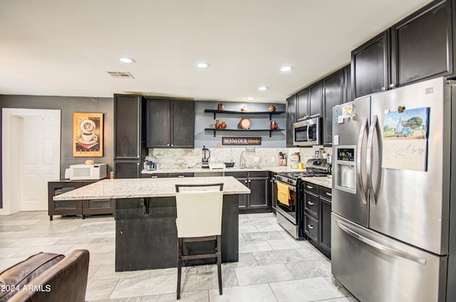 kitchen with stainless steel appliances, tasteful backsplash, light stone countertops, a breakfast bar area, and a center island