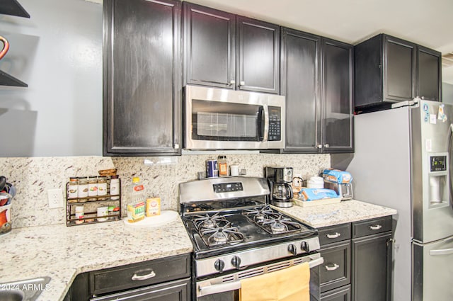 kitchen featuring backsplash, appliances with stainless steel finishes, and light stone counters