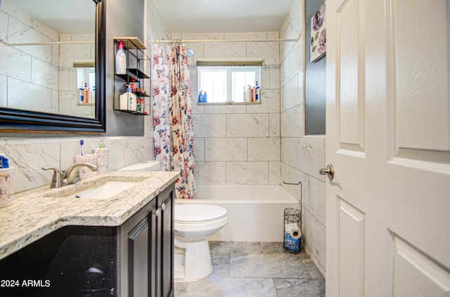 full bathroom featuring shower / bath combo with shower curtain, vanity, toilet, and tile walls