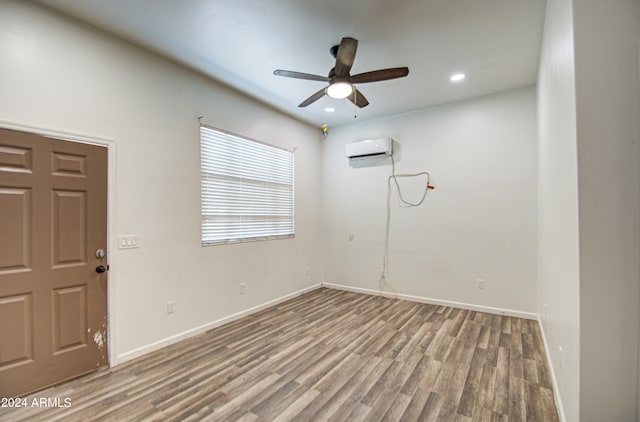 spare room with hardwood / wood-style floors, ceiling fan, and a wall mounted AC