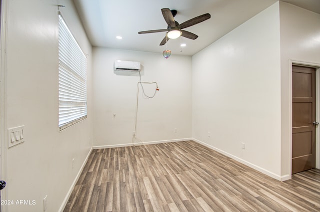 unfurnished room with ceiling fan, a wall mounted AC, and light hardwood / wood-style floors