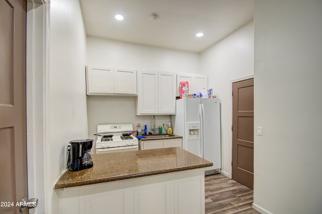 kitchen featuring white cabinetry, sink, dark stone countertops, white appliances, and light wood-type flooring