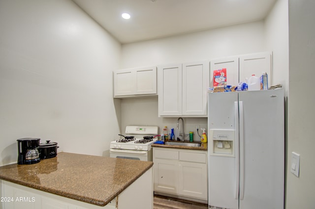 kitchen featuring white cabinetry, sink, dark stone countertops, hardwood / wood-style floors, and white appliances