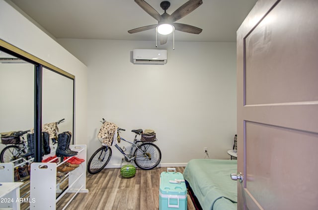 interior space featuring a wall unit AC, wood-type flooring, and ceiling fan