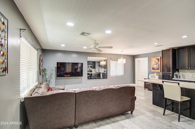 living room featuring ceiling fan with notable chandelier