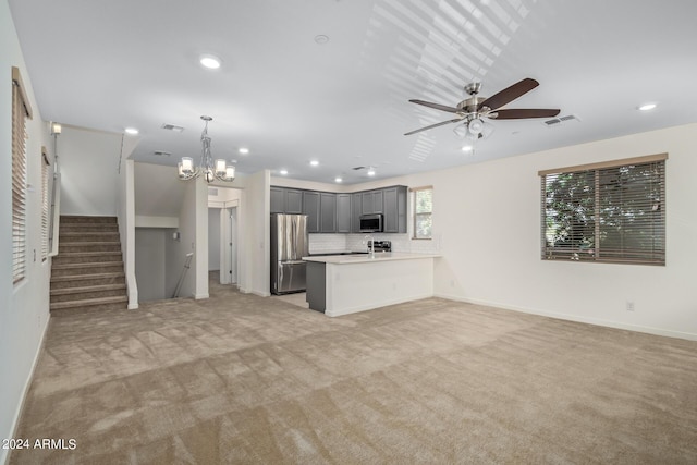 unfurnished living room with ceiling fan with notable chandelier, light colored carpet, and sink