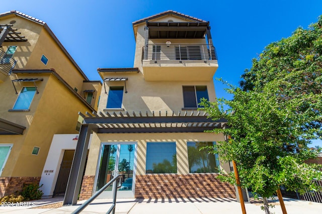 rear view of property with a pergola and a balcony