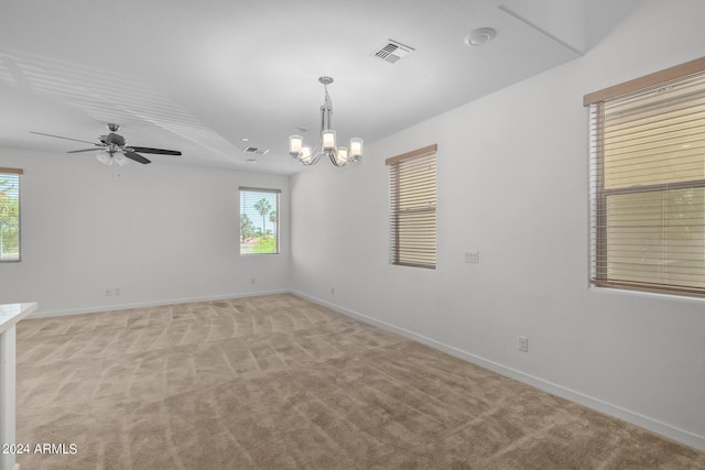 spare room with ceiling fan with notable chandelier, light colored carpet, and a wealth of natural light