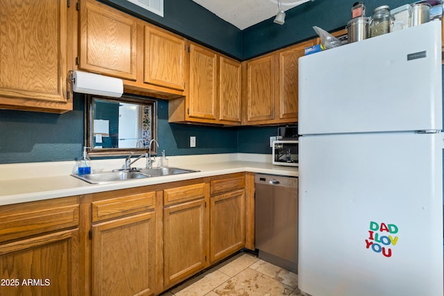 kitchen with freestanding refrigerator, dishwasher, a sink, light countertops, and light tile patterned floors