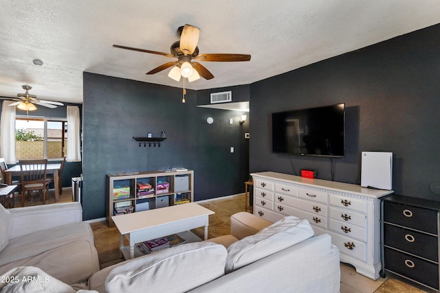 living room featuring a ceiling fan, a textured ceiling, and light tile patterned floors