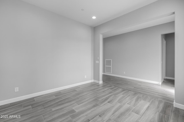 empty room with wood finished floors, visible vents, and baseboards