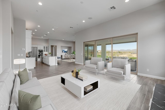 living area with light wood-type flooring, visible vents, baseboards, and recessed lighting