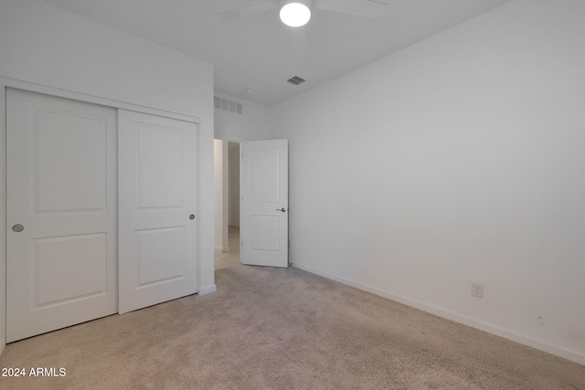 unfurnished bedroom featuring ceiling fan, light carpet, and a closet