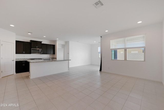 kitchen featuring light tile patterned flooring, a center island with sink, and sink