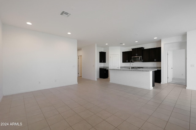 kitchen featuring light tile patterned floors, a center island with sink, and sink