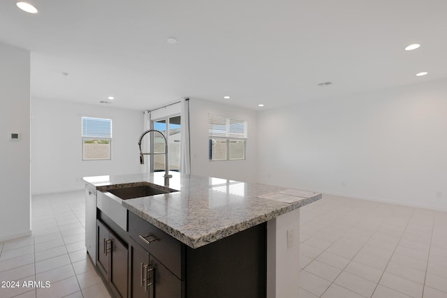 kitchen featuring light stone counters, sink, dishwasher, an island with sink, and light tile patterned flooring