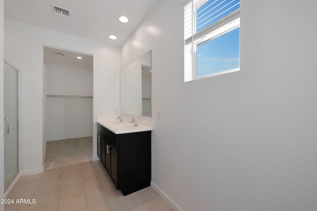 bathroom featuring tile patterned floors, a shower with door, and vanity