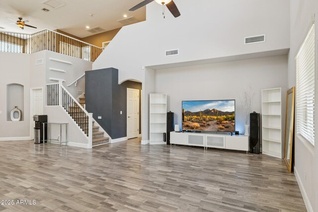 46141 W Rainbow Dr, Maricopa, AZ 85139 - unfurnished living room with ceiling fan, a towering ceiling, arched walkways, wood finished floors, and plenty of natural light