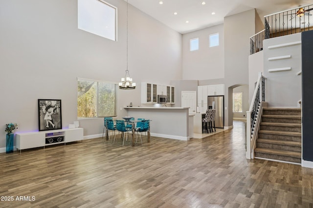 46141 W Rainbow Dr, Maricopa, AZ 85139 - living room featuring a high ceiling, arched walkways, a chandelier, stairs, and wood finished floors