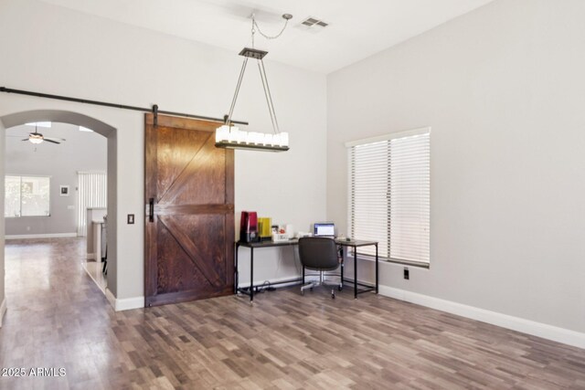 46141 W Rainbow Dr, Maricopa, AZ 85139 - office with a barn door, wood finished floors, arched walkways, and a ceiling fan