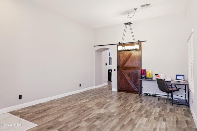 46141 W Rainbow Dr, Maricopa, AZ 85139 - living area featuring wood finished floors, a barn door, arched walkways, and a desk