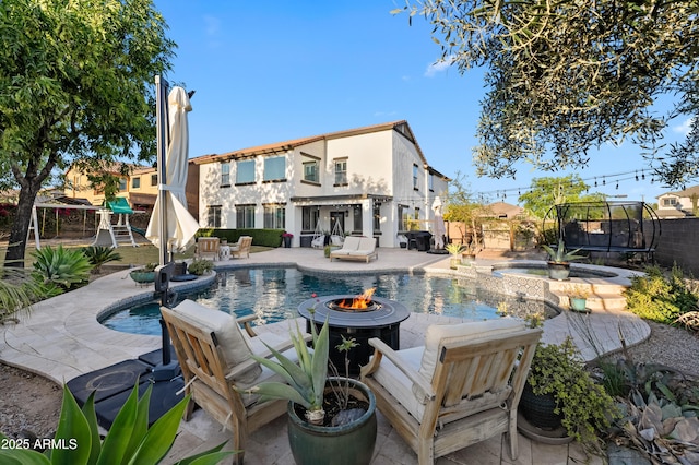 view of pool with a trampoline, an outdoor fire pit, a fenced in pool, a fenced backyard, and a patio
