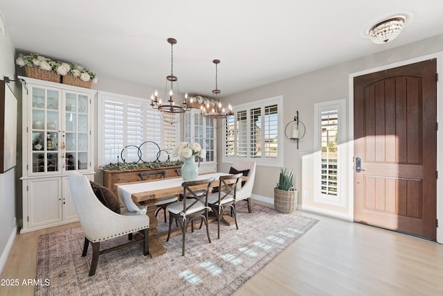 dining space featuring baseboards, wood finished floors, and a notable chandelier