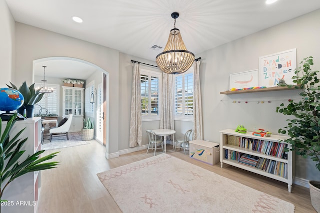 interior space featuring an inviting chandelier, arched walkways, wood finished floors, and visible vents