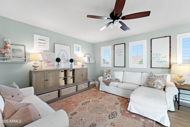 living area featuring baseboards, a ceiling fan, wood finished floors, and a wealth of natural light