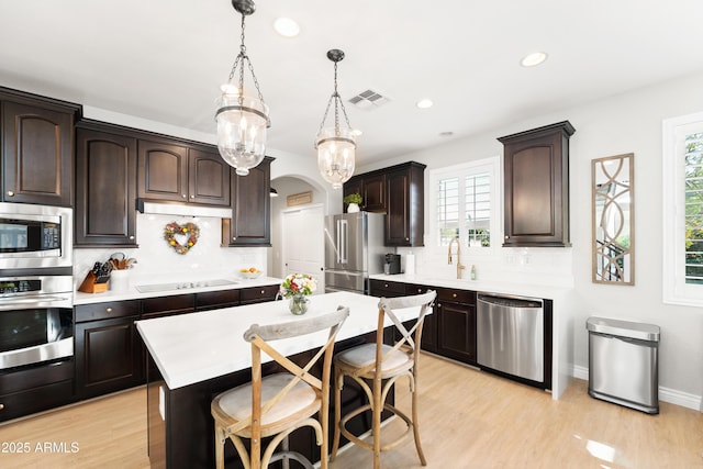 kitchen with backsplash, dark brown cabinets, light countertops, stainless steel appliances, and recessed lighting
