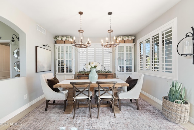 dining room with baseboards, arched walkways, a notable chandelier, and visible vents