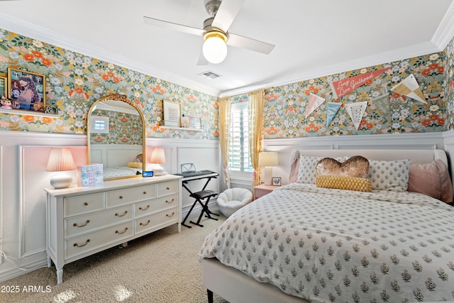 carpeted bedroom with visible vents, wainscoting, crown molding, and wallpapered walls
