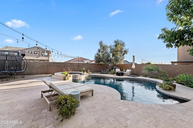 view of swimming pool featuring a patio, a fenced backyard, a trampoline, and a pool with connected hot tub