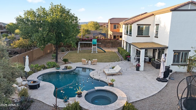view of swimming pool featuring a patio, a playground, and an in ground hot tub