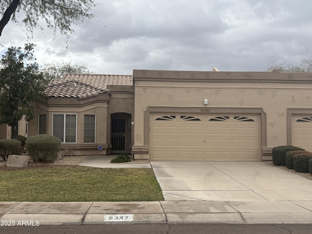 view of front of home featuring stucco siding, a tiled roof, concrete driveway, and a garage