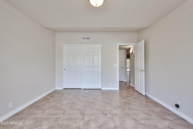 unfurnished bedroom with light tile patterned floors, a closet, baseboards, and visible vents