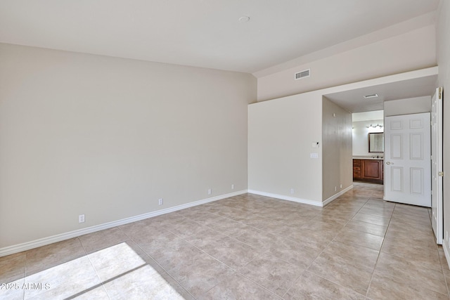 unfurnished room featuring vaulted ceiling, light tile patterned flooring, baseboards, and visible vents