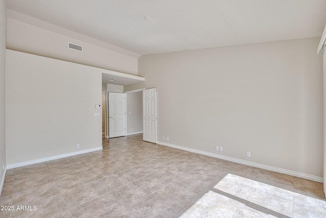 spare room featuring vaulted ceiling, light tile patterned floors, baseboards, and visible vents