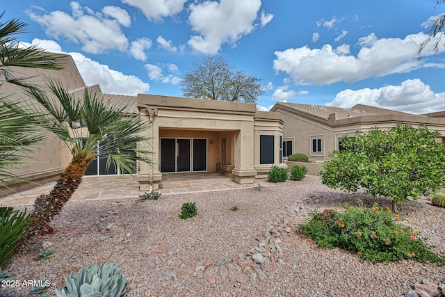 rear view of house with stucco siding and a tiled roof