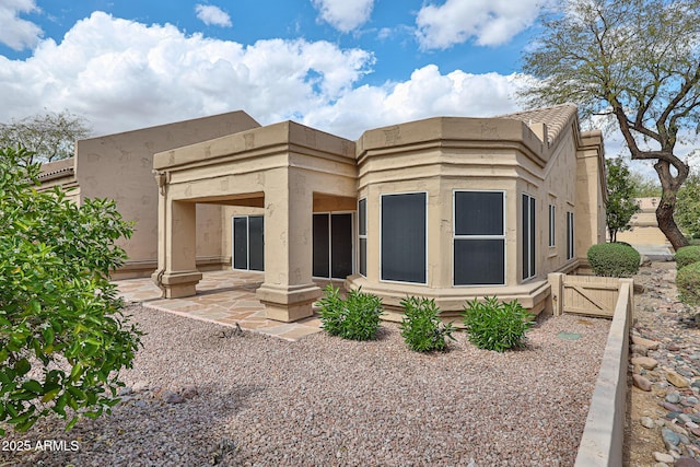 back of property featuring a patio and a gate