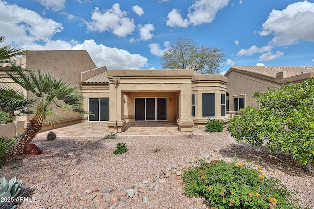 back of property with stucco siding, a tile roof, a patio, and fence