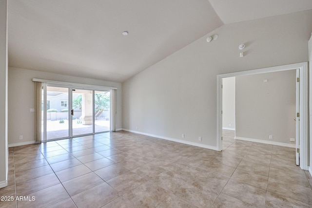 spare room with vaulted ceiling, light tile patterned floors, and baseboards