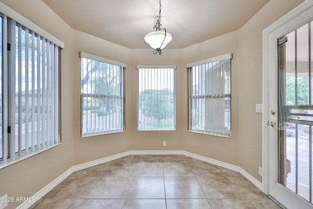 unfurnished dining area with a wealth of natural light, baseboards, and light tile patterned floors