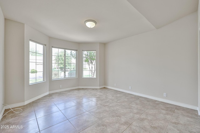 empty room featuring baseboards and light tile patterned flooring