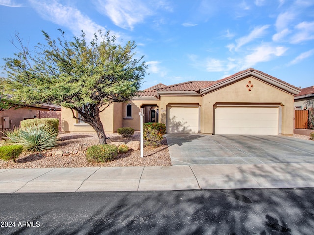 mediterranean / spanish-style home with concrete driveway, a tile roof, an attached garage, and stucco siding