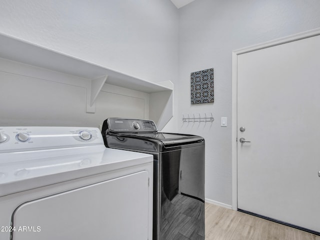 washroom with washing machine and clothes dryer and light hardwood / wood-style flooring