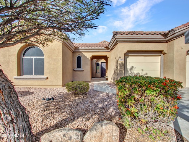 view of front of house with a garage, a tile roof, and stucco siding