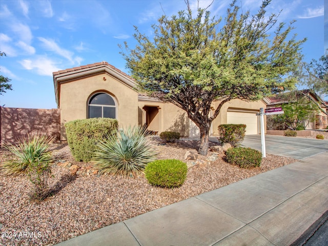 mediterranean / spanish house with a garage, a tile roof, concrete driveway, and stucco siding